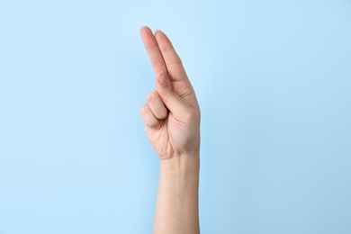 Woman showing U letter on color background, closeup. Sign language