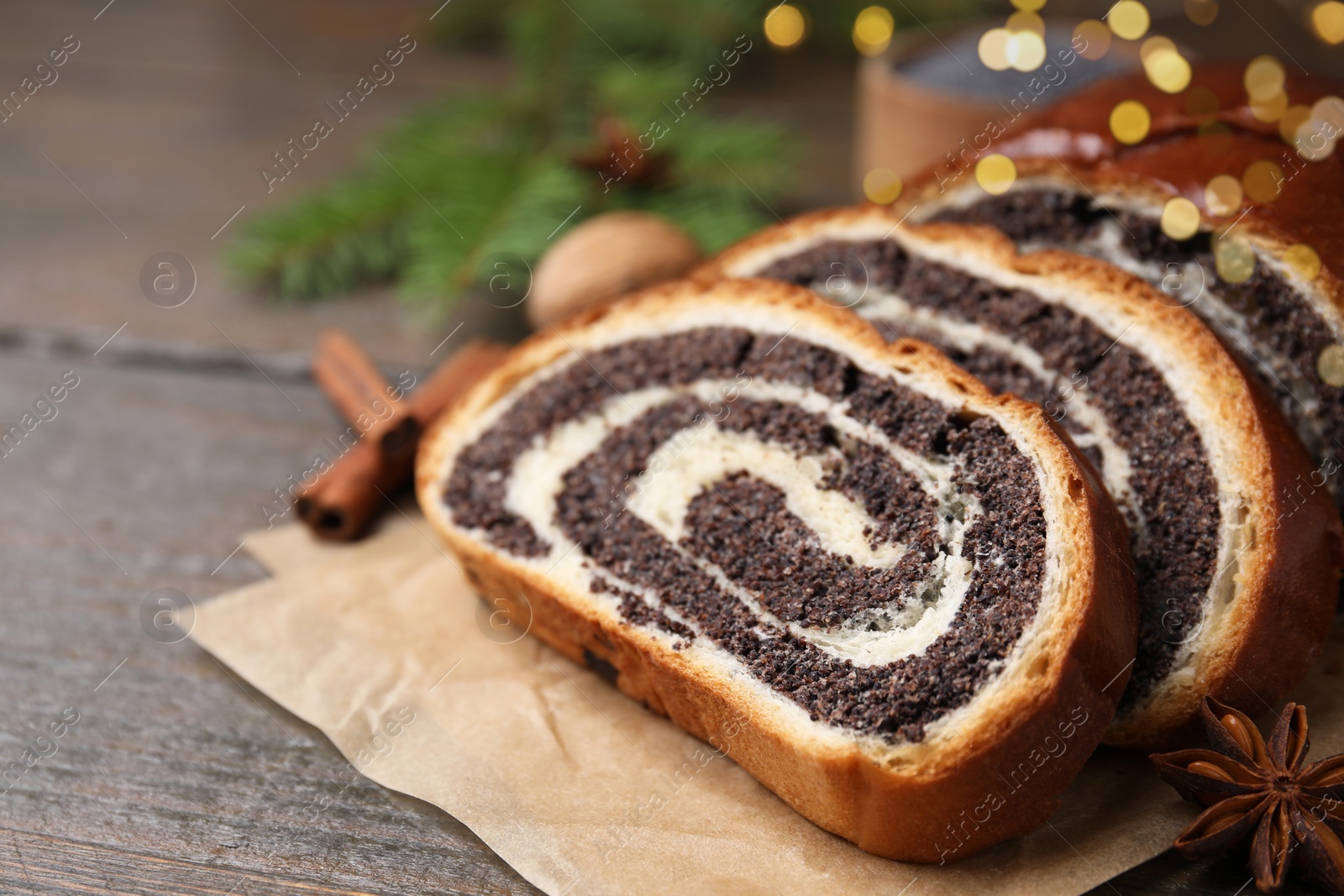 Photo of Slices of poppy seed roll and anise star on wooden table, closeup with space for text. Tasty cake