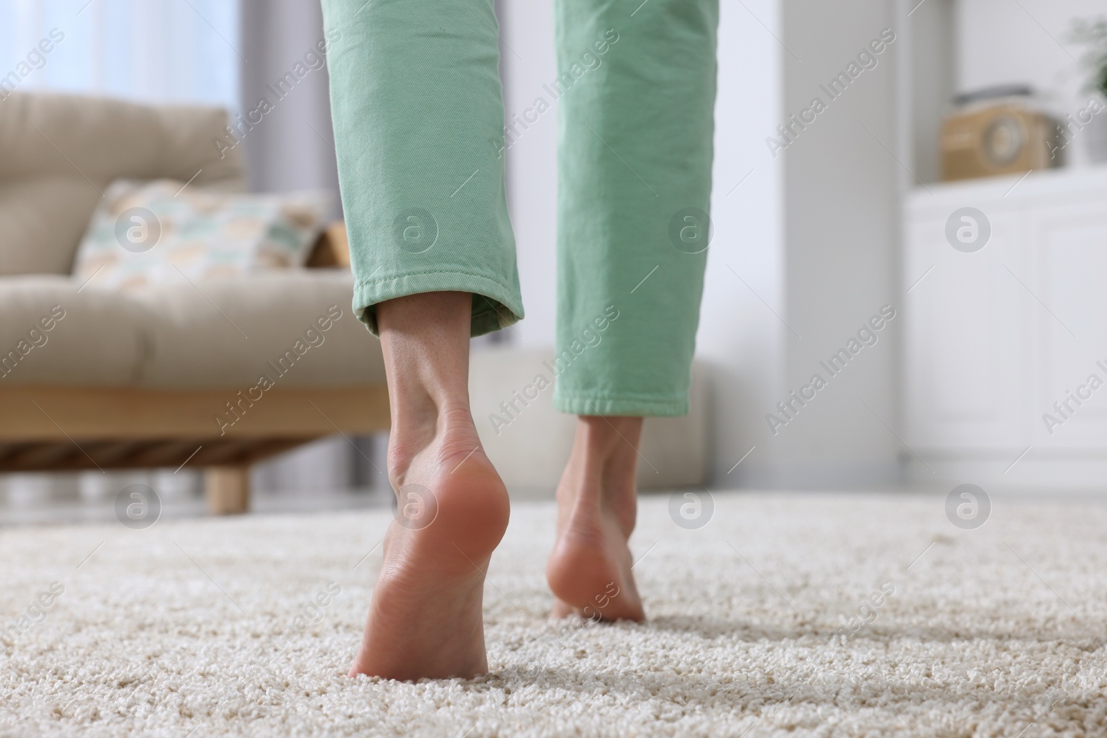 Photo of Woman walking on soft beige carpet at home, closeup