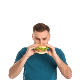 Young man eating tasty burger on white background