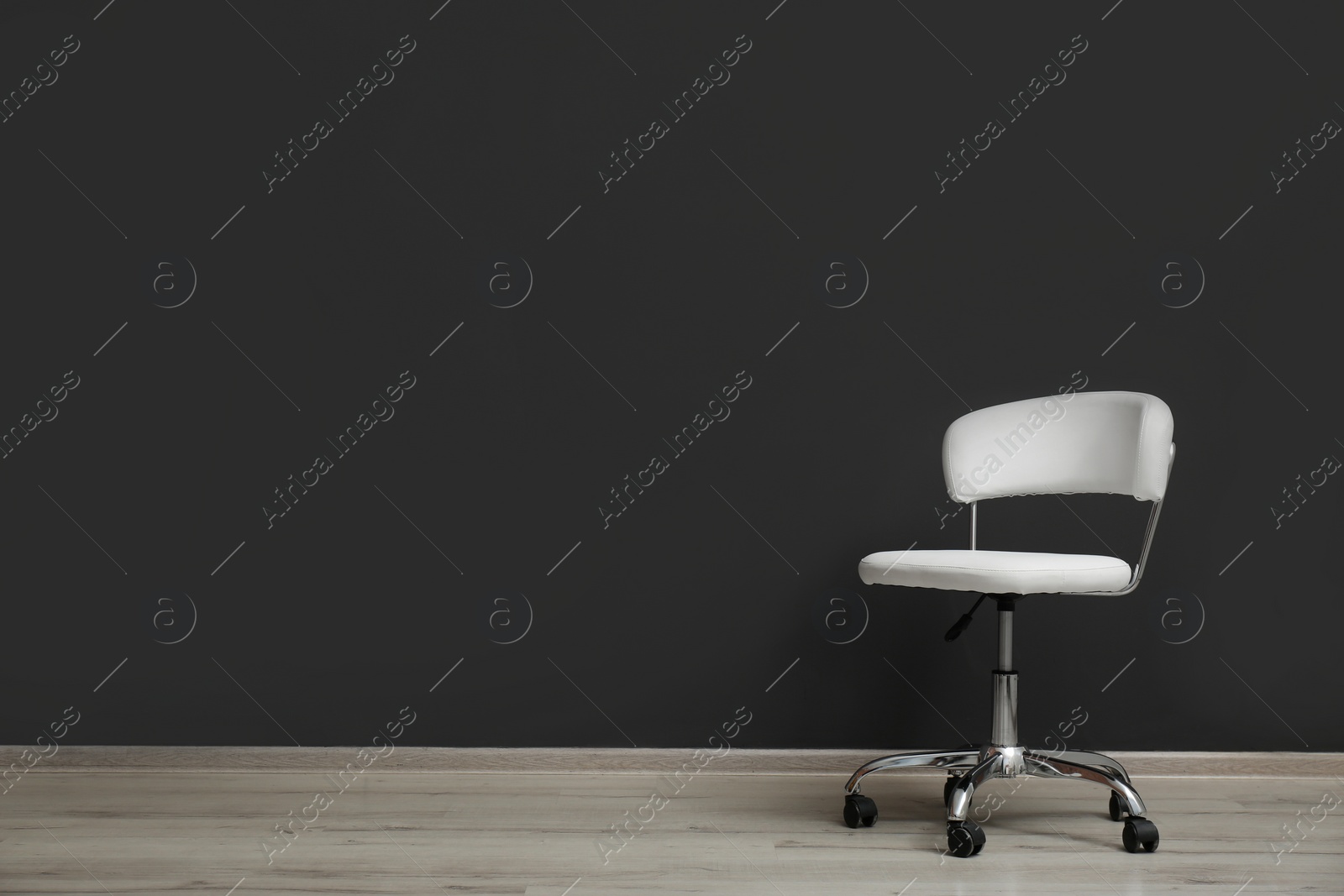 Photo of Comfortable office chair near black wall indoors. Space for text