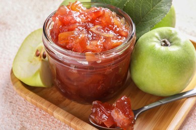 Photo of Glass jar of delicious apple jam and fresh fruits on light table, closeup