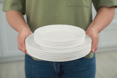 Photo of Woman holding plates in kitchen, closeup view