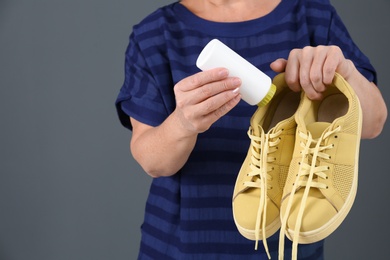 Photo of Woman putting powder shoe freshener in footwear on color background, closeup