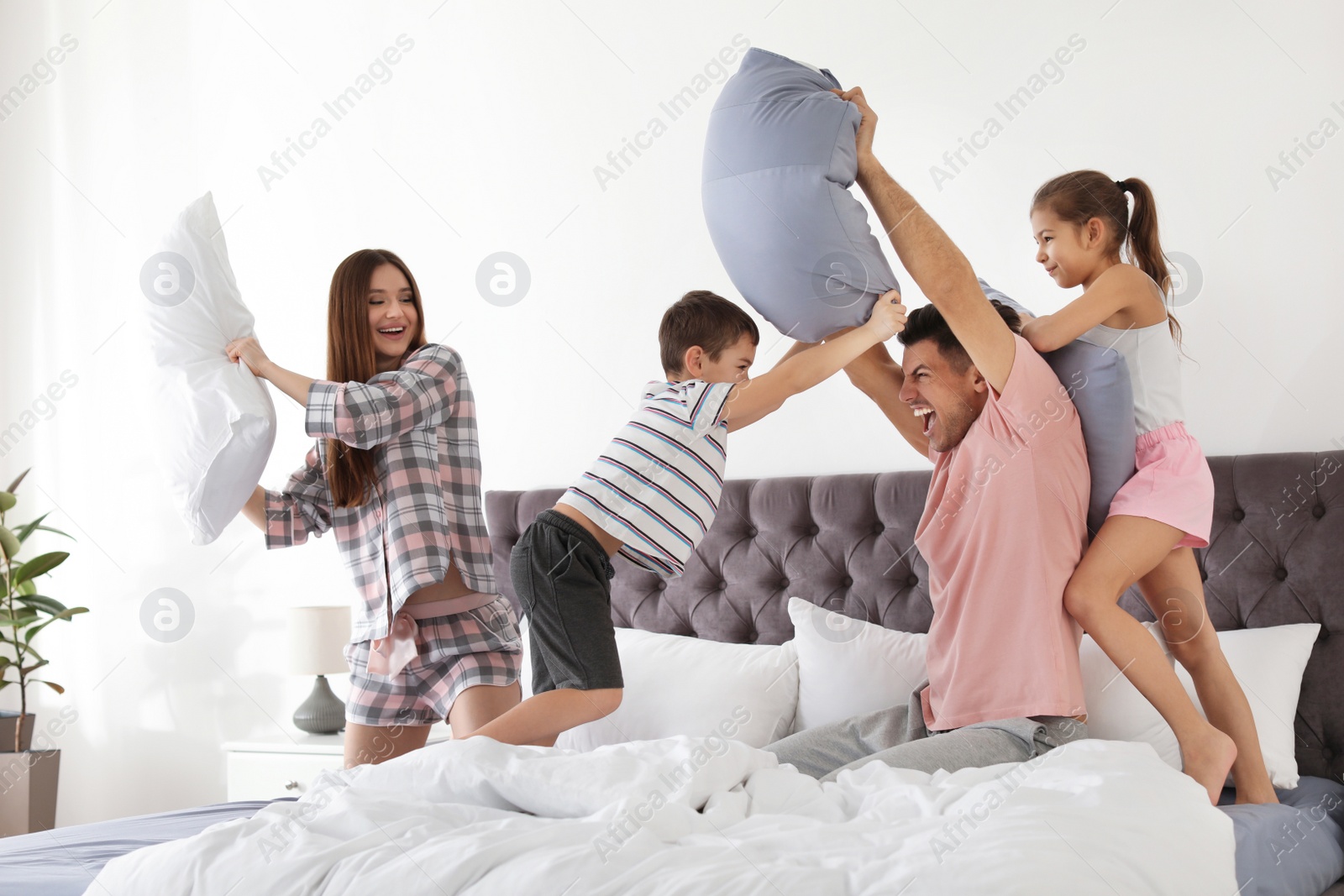 Photo of Happy family having pillow fight in bedroom