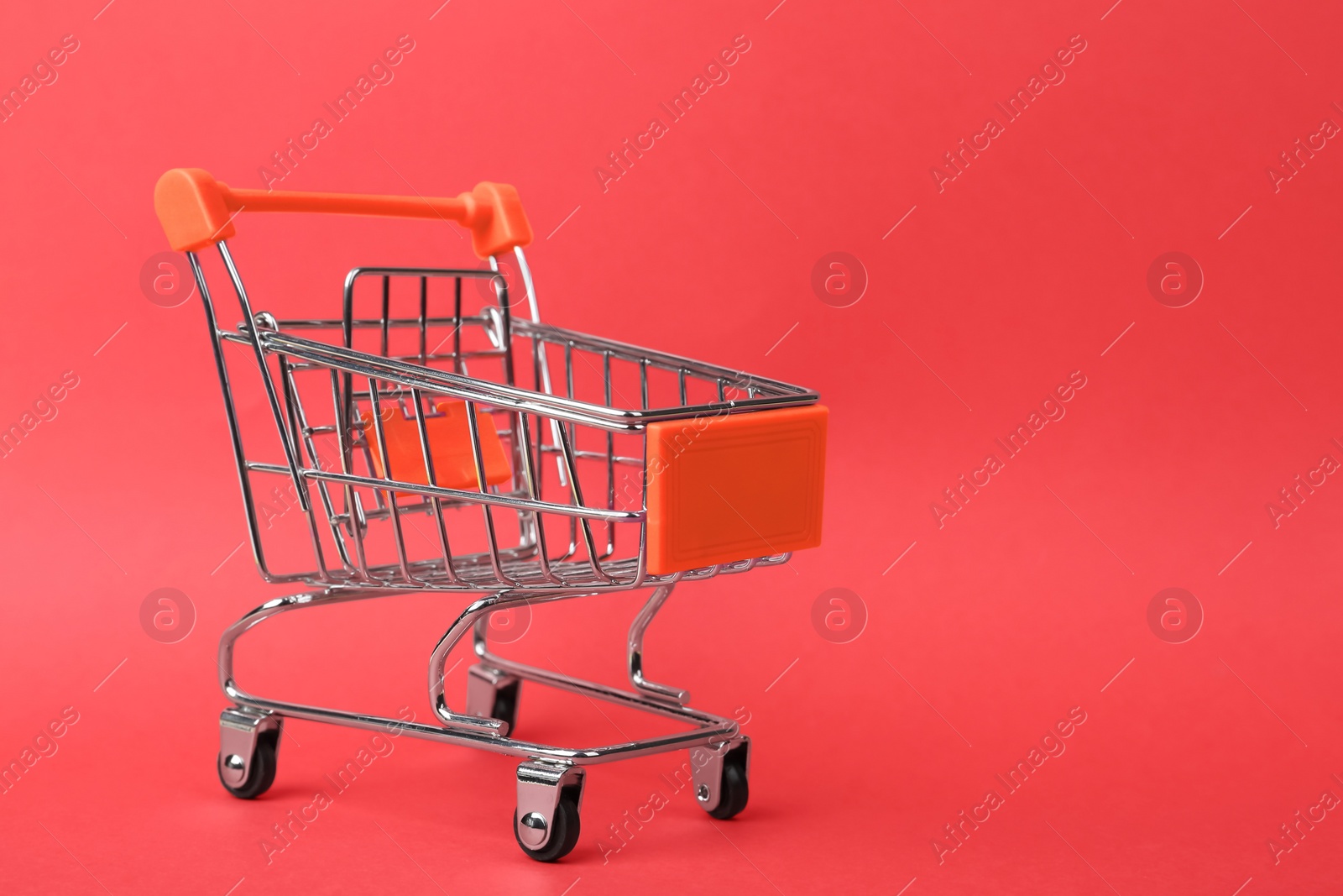 Photo of Empty shopping trolley on color background. Space for text