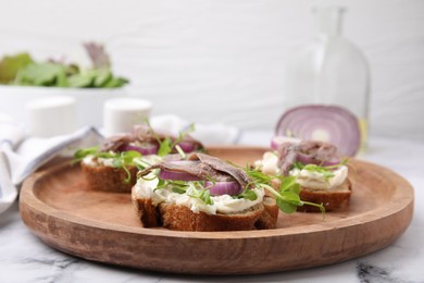 Photo of Delicious bruschettas with anchovies, cream cheese, red onion and greens on white marble table