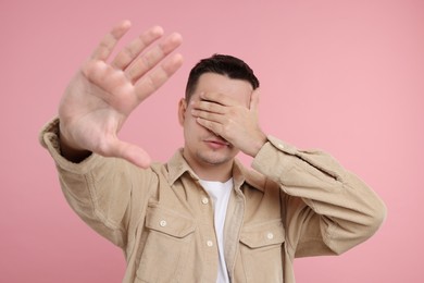 Photo of Embarrassed man covering face with hand on pink background