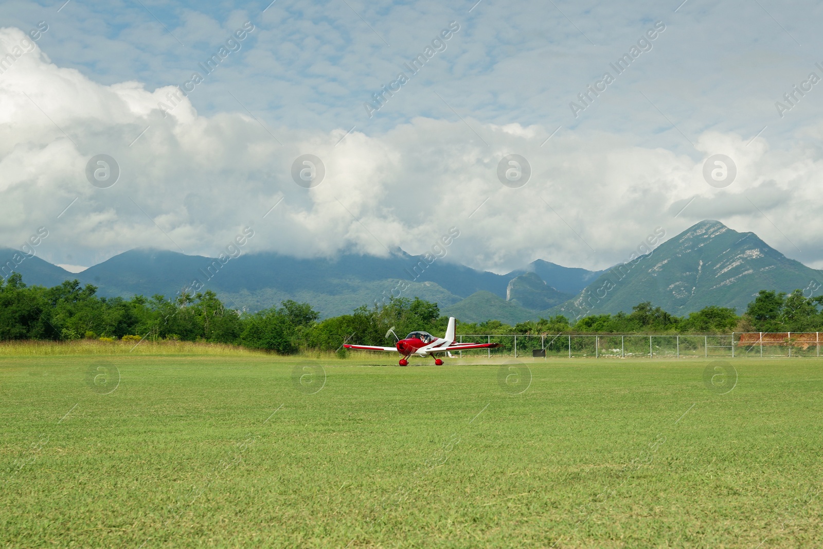 Photo of Modern airplane on green grass against mountains background