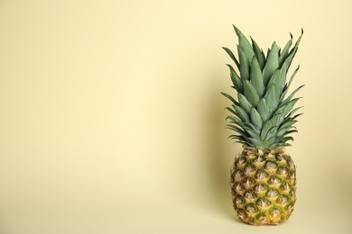 Photo of Ripe juicy pineapple on light yellow background. Space for text