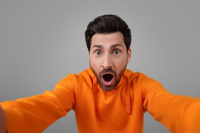 Photo of Emotional man taking selfie on grey background
