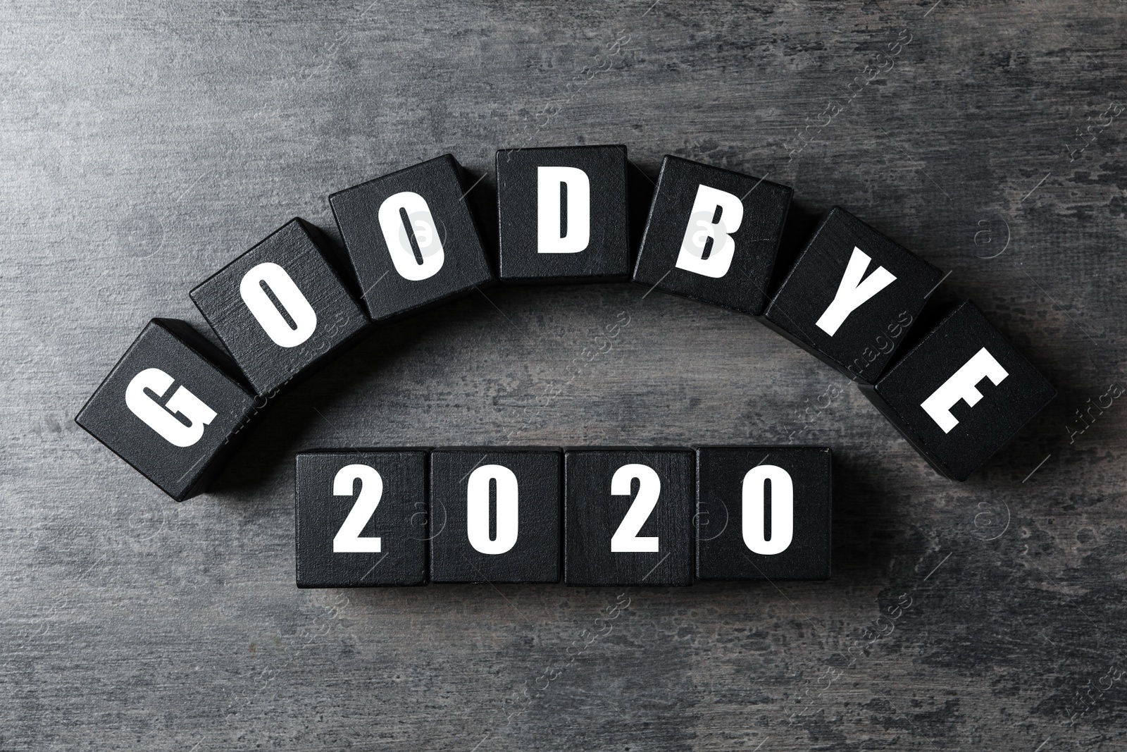 Photo of Black cubes with phrase Goodbye 2020 on grey table, flat lay