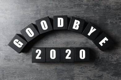 Black cubes with phrase Goodbye 2020 on grey table, flat lay