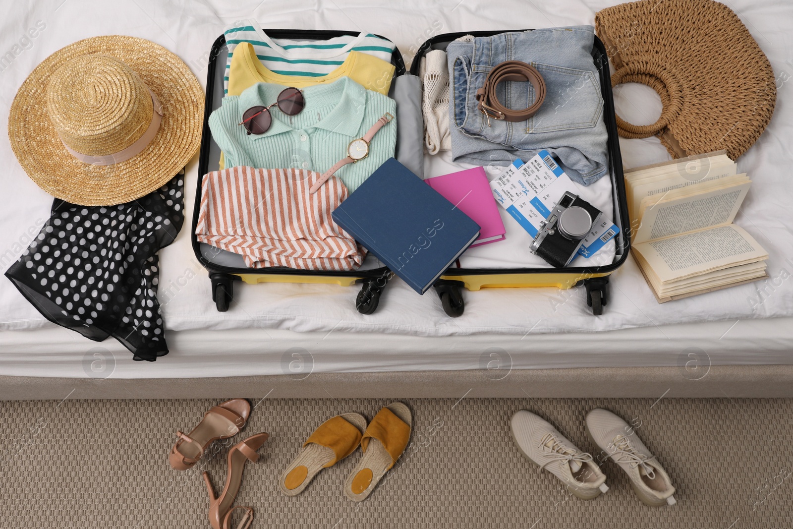 Photo of Open suitcase with clothes and accessories on bed indoors, top view