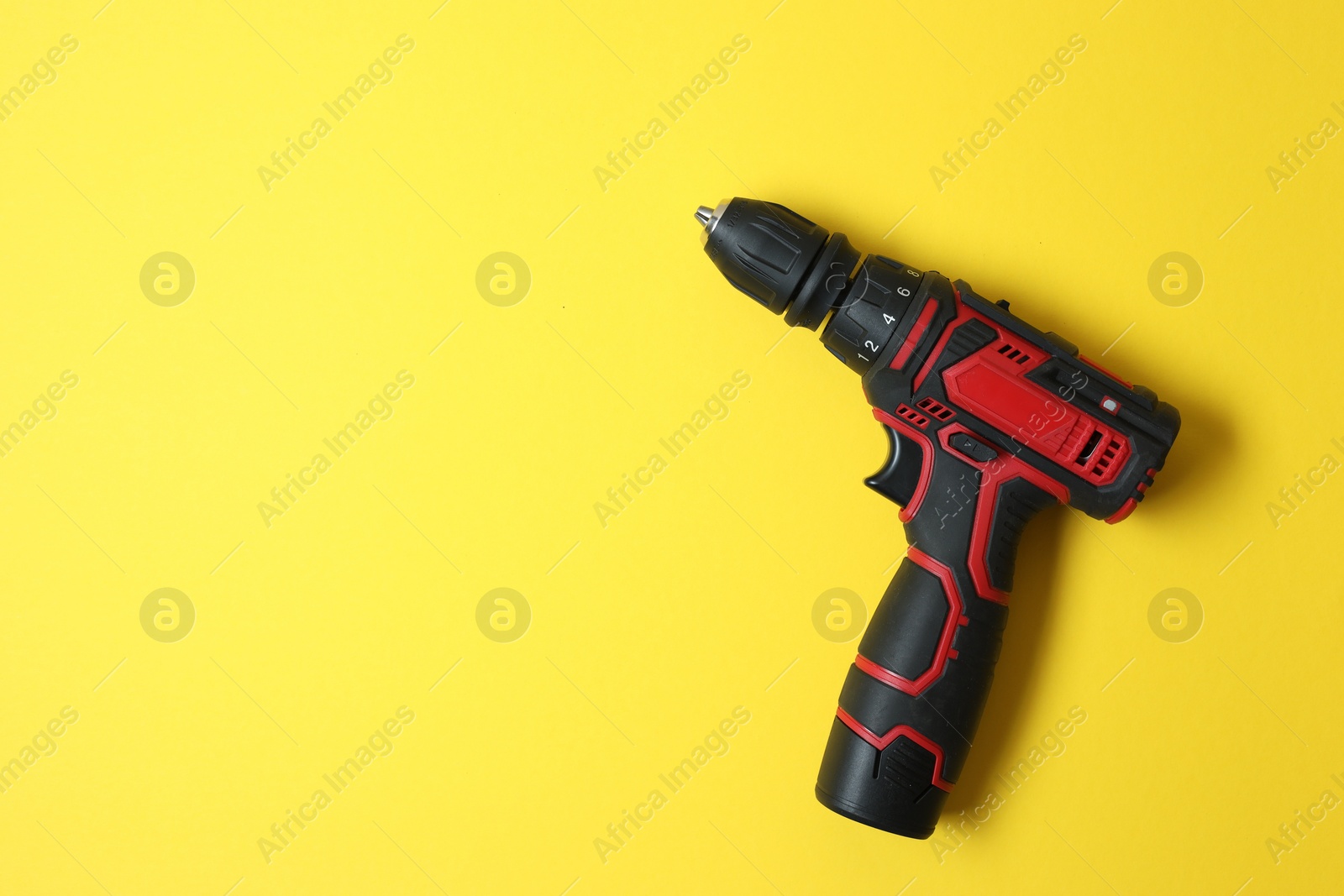 Photo of Electric screwdriver on yellow background, top view. Space for text