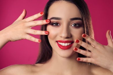 Beautiful woman with stylish nail polish on color background