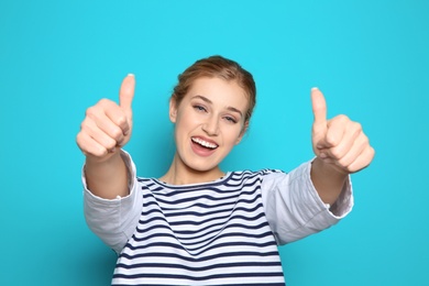Photo of Happy young woman showing thumbs up on color background. Celebrating victory