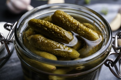 Photo of Glass jar of tasty pickled cucumbers, closeup