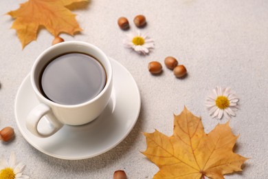 Composition with cup of hot drink and autumn leaves on light grey textured table