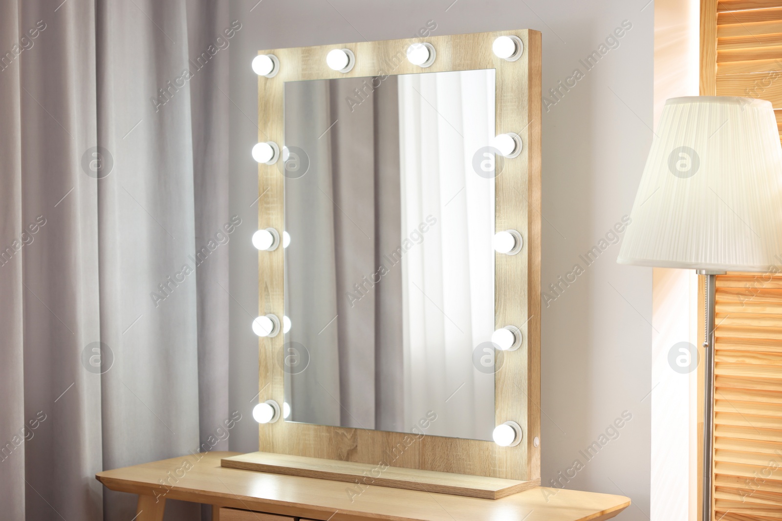 Photo of Beautiful mirror with light bulbs and lamp in makeup room