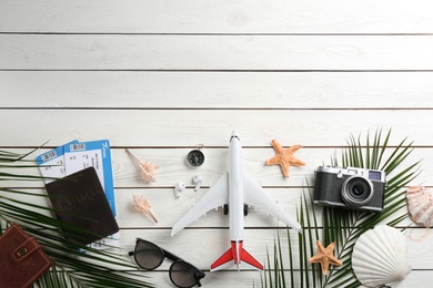 Flat lay composition with toy airplane and travel items on white wooden background. Space for text