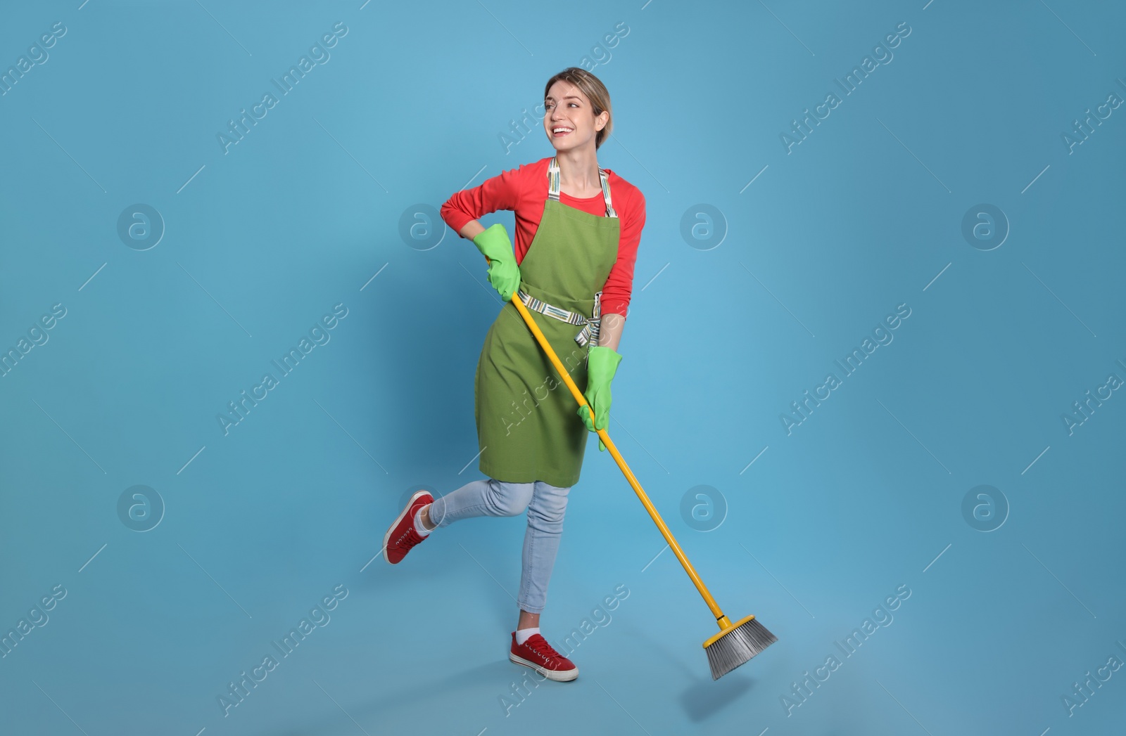 Photo of Young housewife with broom on light blue background