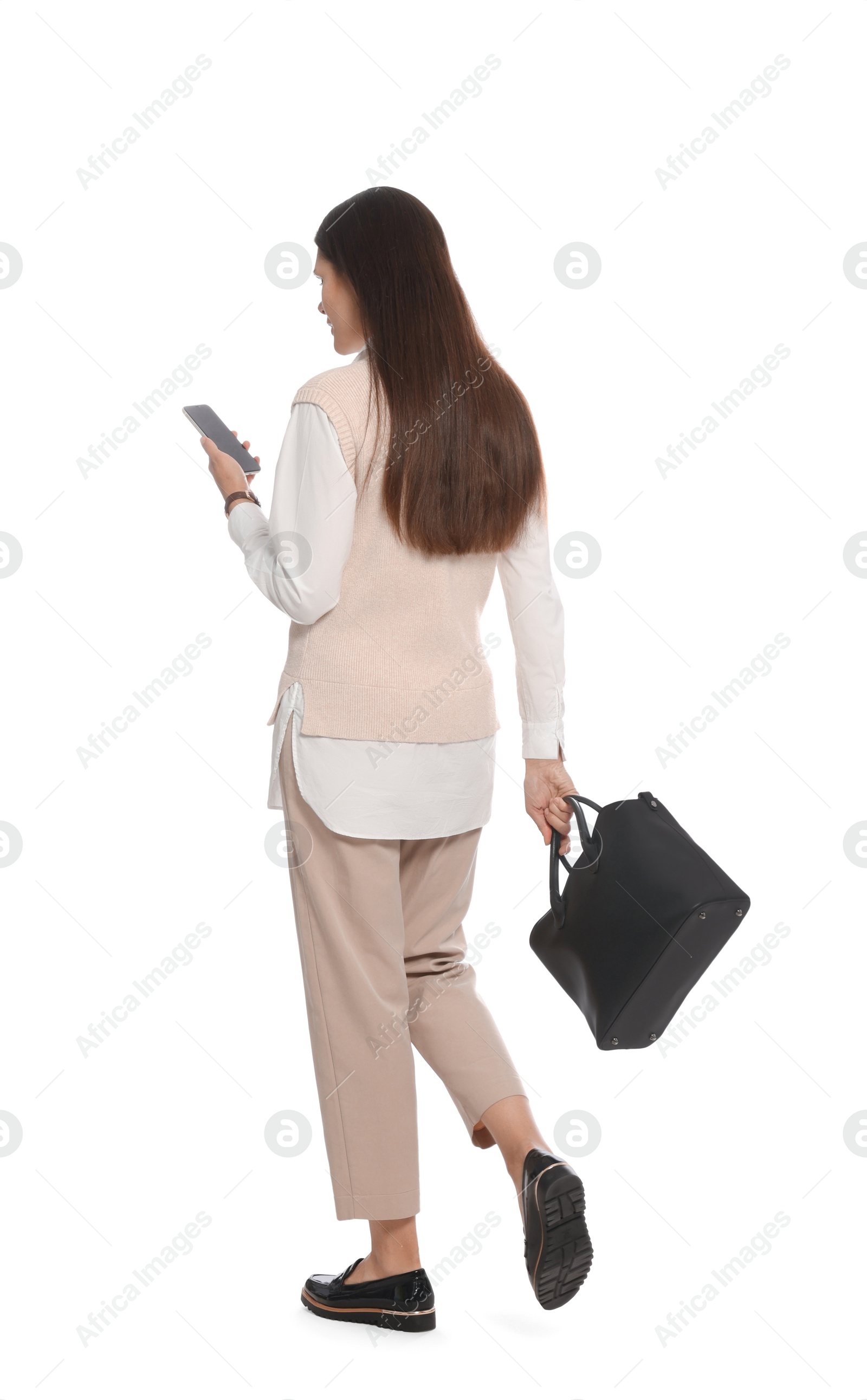 Photo of Young woman with stylish leather bag and smartphone walking on white background