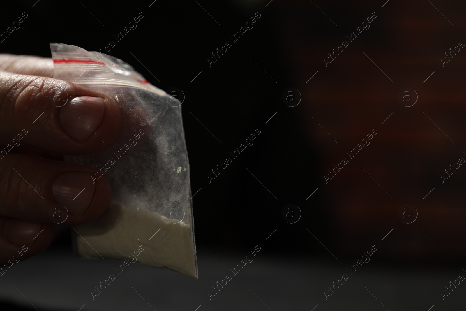Photo of Addicted man with plastic bag of hard drug on blurred background, closeup. Space for text
