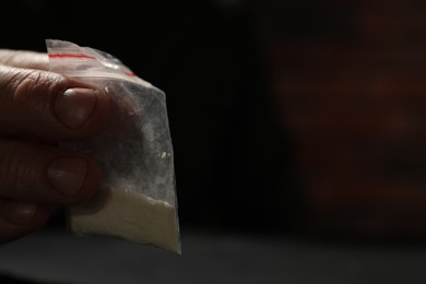 Addicted man with plastic bag of hard drug on blurred background, closeup. Space for text