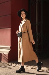 Photo of Beautiful young woman with stylish waist bag on city street