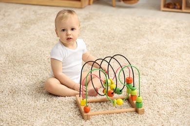 Photo of Children toys. Cute little boy and bead maze on rug at home