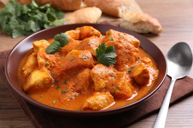 Photo of Bowl of delicious chicken curry on wooden table, closeup