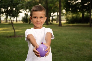 Photo of Cute little boy holding water bomb in park