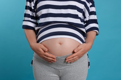 Photo of Pregnant woman on light blue background, closeup