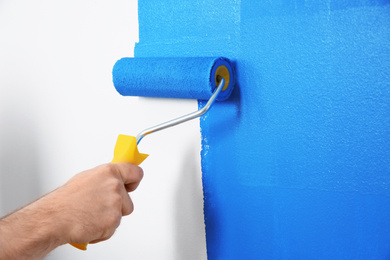 Photo of Man painting white wall with blue dye, closeup. Interior renovation