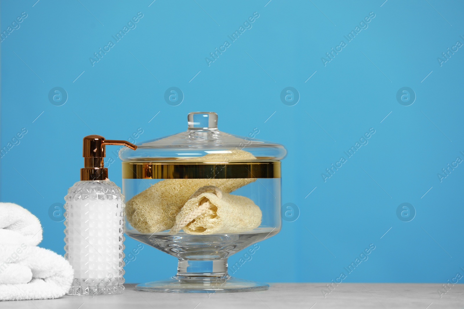 Photo of Composition of glass jar with luffa sponges on table near pink wall. Space for text