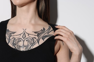 Woman with cool tattoos on light background, closeup
