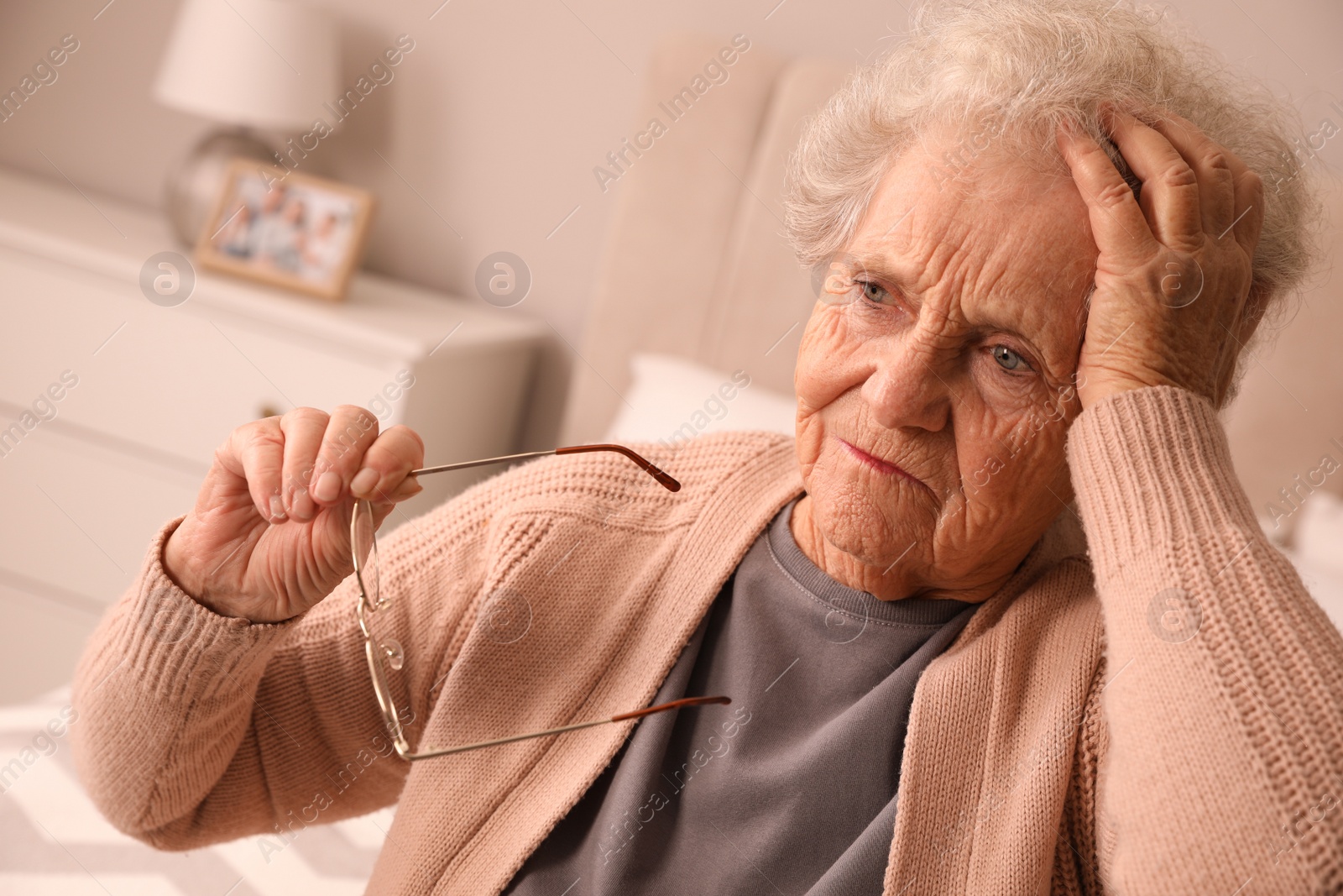 Photo of Senior woman with headache in bedroom at home