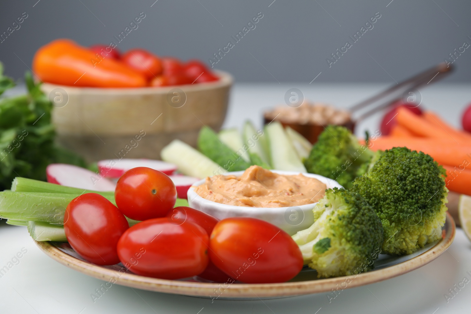 Photo of Plate with delicious hummus and fresh vegetables on white table, closeup