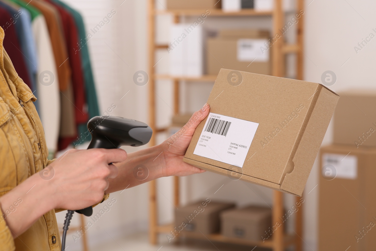 Photo of Seller with scanner reading parcel barcode in office, closeup. Online store