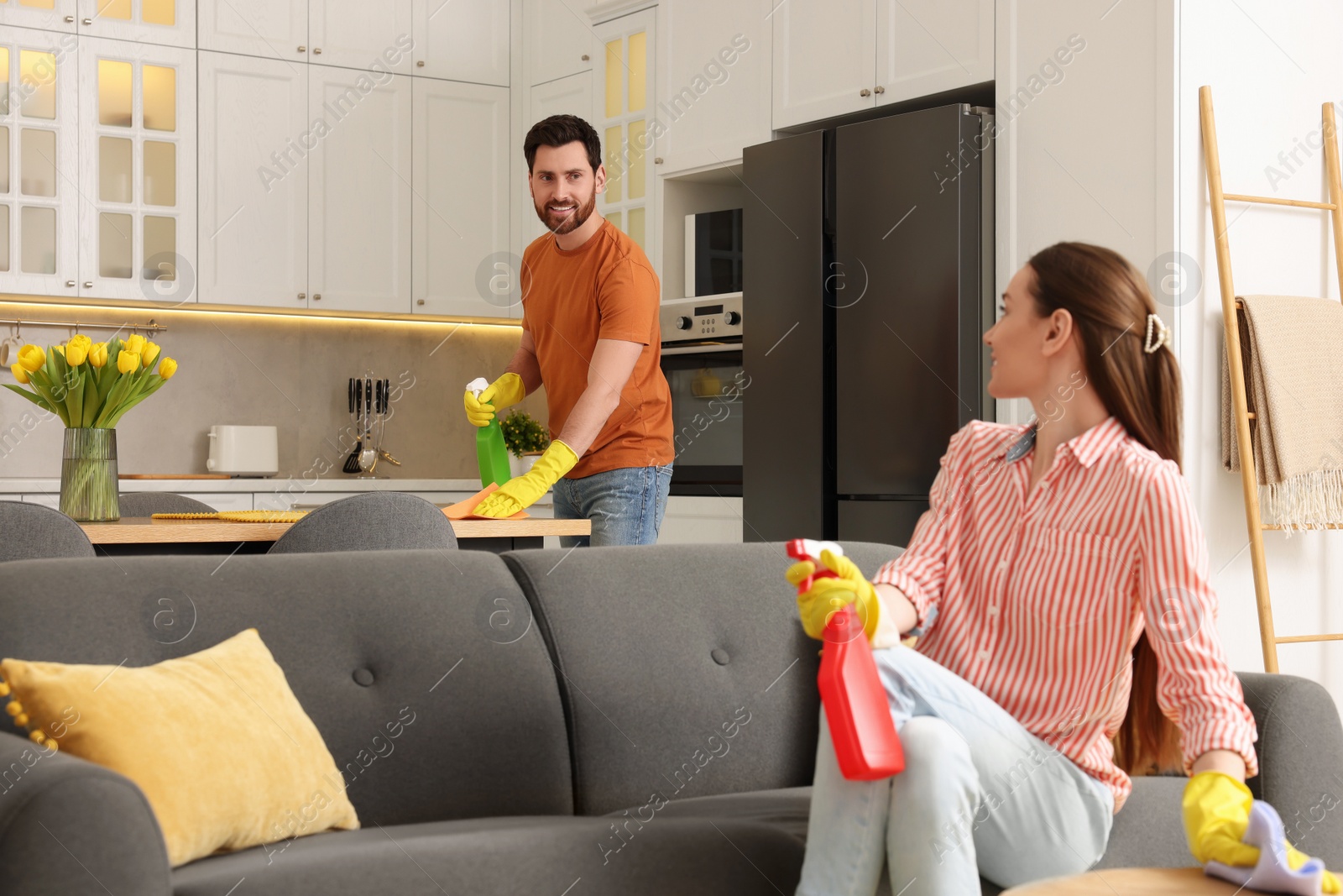 Photo of Spring cleaning. Lovely couple tidying up living room and kitchen together