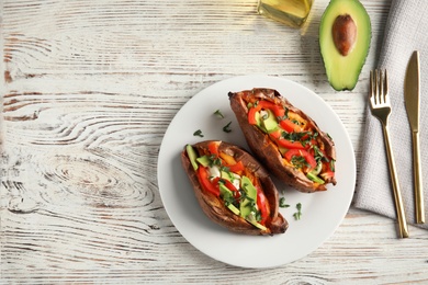 Photo of Plate with stuffed sweet potatoes served on white wooden table, top view. Space for text