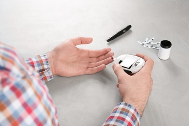 Man checking blood sugar level with glucometer at table. Diabetes test