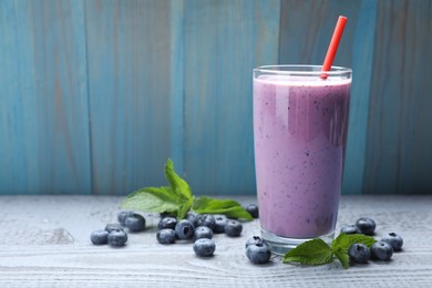Glass of freshly made blueberry smoothie on grey wooden table. Space for text