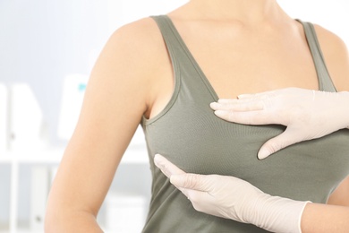 Photo of Doctor checking woman's breast at hospital, closeup