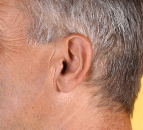 Photo of Mature man on color background, closeup. Hearing problem