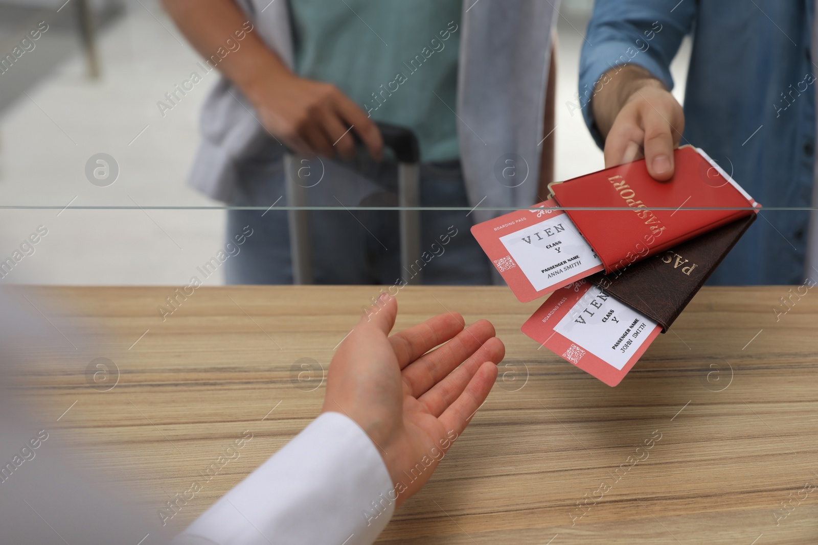 Photo of Man giving passports with tickets to agent at check-in desk in airport, closeup