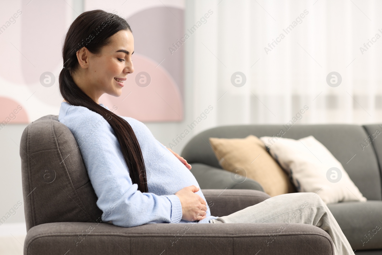 Photo of Happy pregnant woman on armchair at home