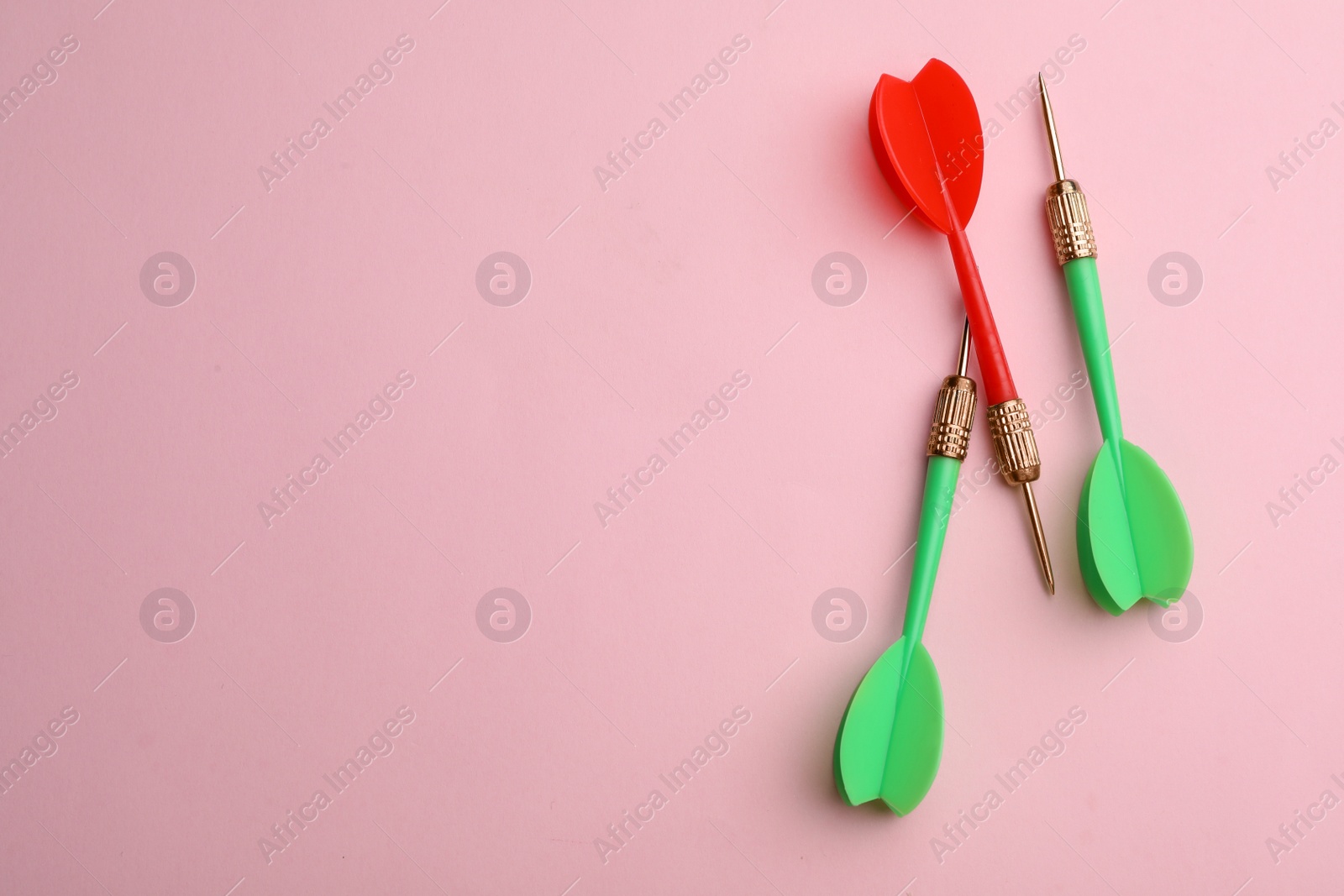 Photo of Plastic dart arrows on pink background, flat lay with space for text