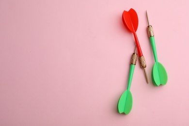 Photo of Plastic dart arrows on pink background, flat lay with space for text